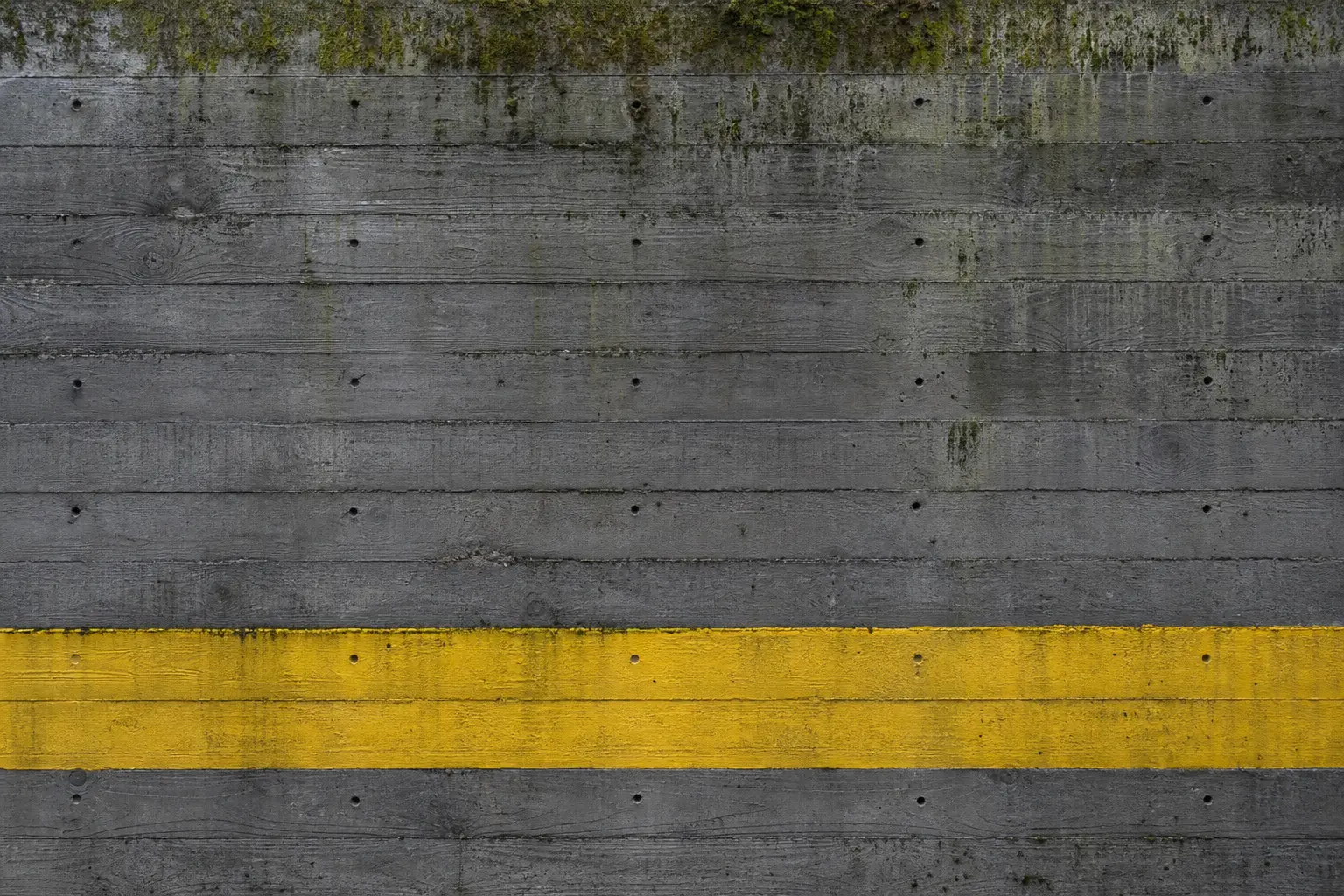 A poured concrete wall with a painted hazard yellow stripe