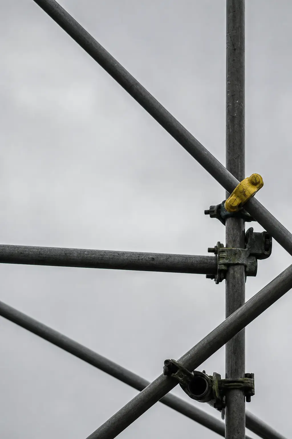Scaffolding poles crossing against a flat grey sky