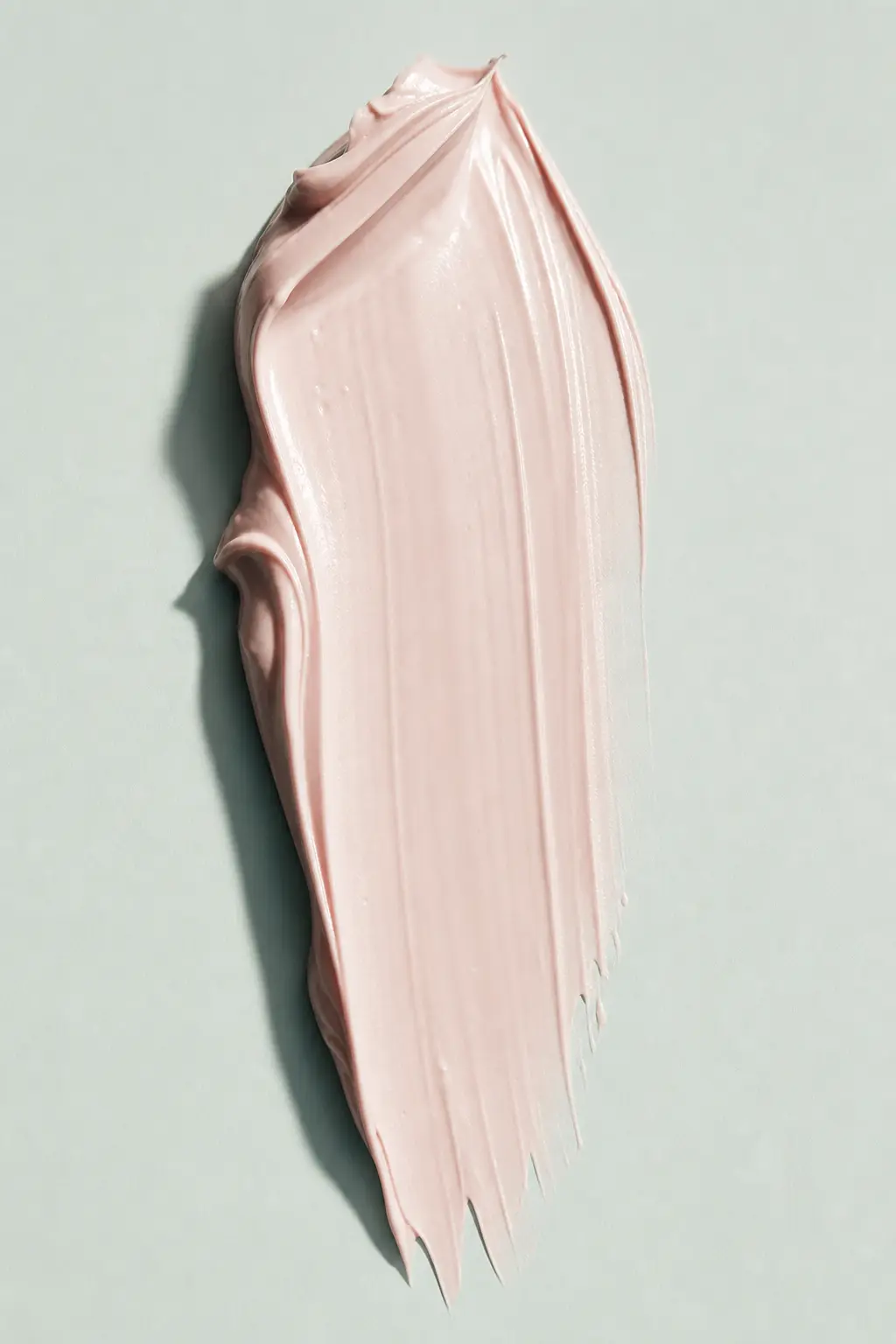 A cream swatch drawn down on a mint surface