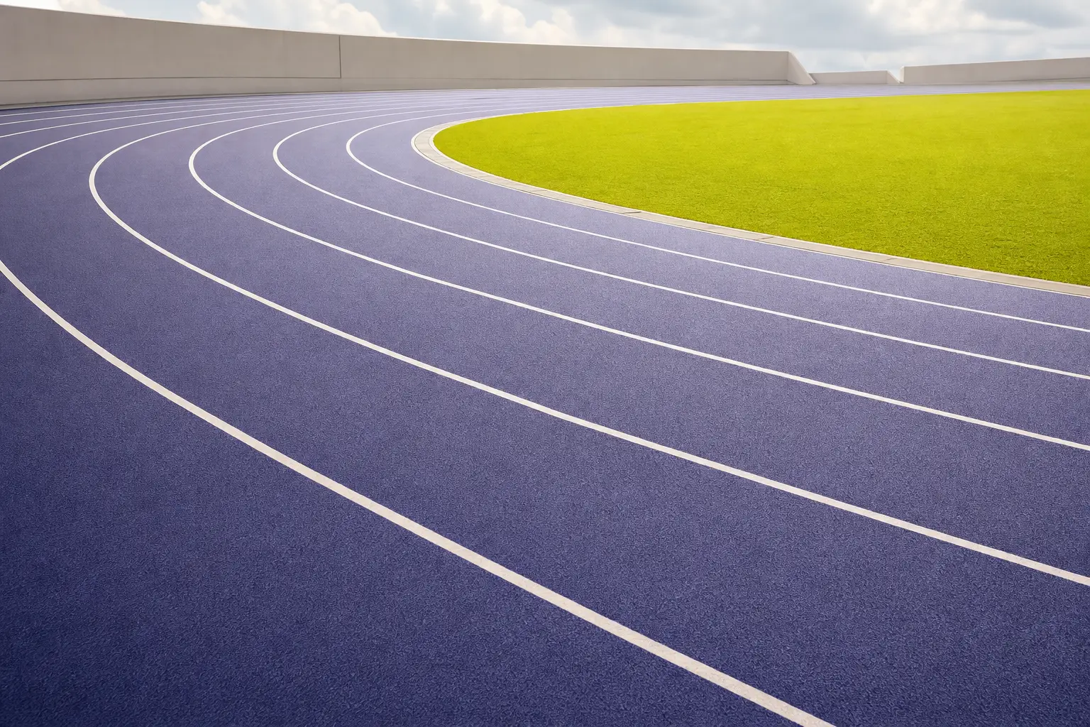 An empty running track curving under bright light
